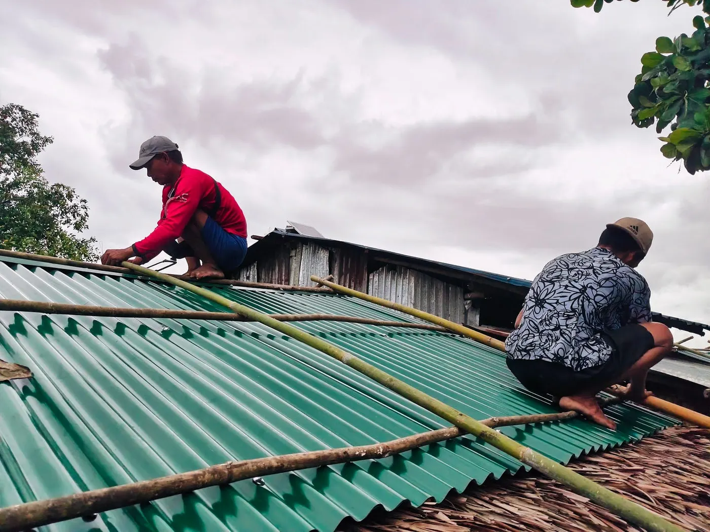 Workers fitting new roof sheets on a house